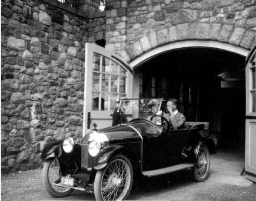 James Scripps Booth (behind the wheel) with brother Warren Scripps Booth in a Scripps-Booth 4-cylinder Model C at Tower Garage at Cranbrook House. Their father George Gough Booth stands next to the car, partially hidden by the windshield.  Circa 1917, Cranbrook Archives. 