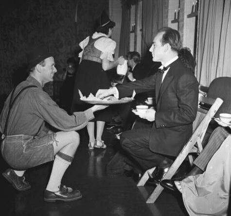 Harry Bertoia is served food by a costumed man at the Cranbrook Academy of Art folk dancing party. December, 1940. Cranbrook Archives. 