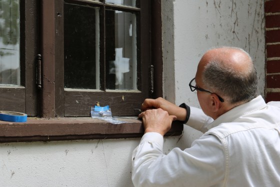 Ron Koenig, the owner of Building Arts & Conservation, takes samples of paint on the window frame at Tower Cottage.